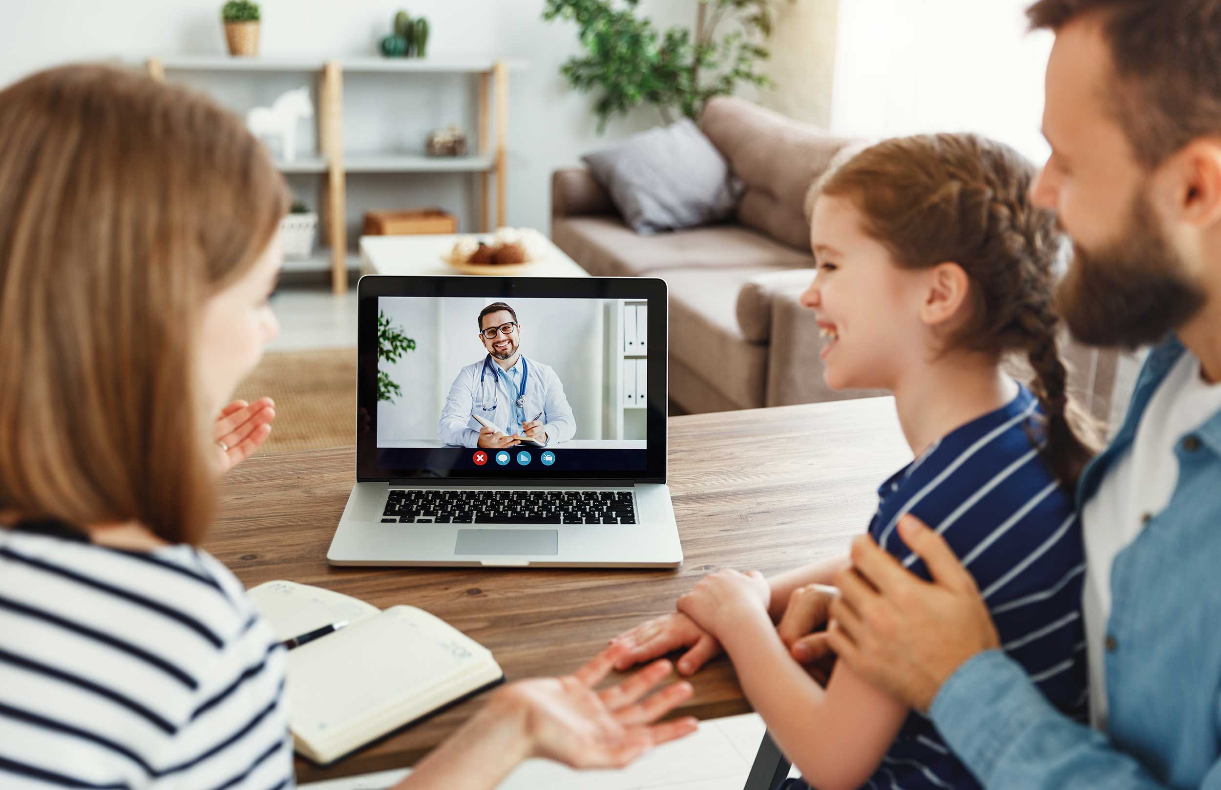 Family gathered around a laptop for a telehealth visit with their doctor